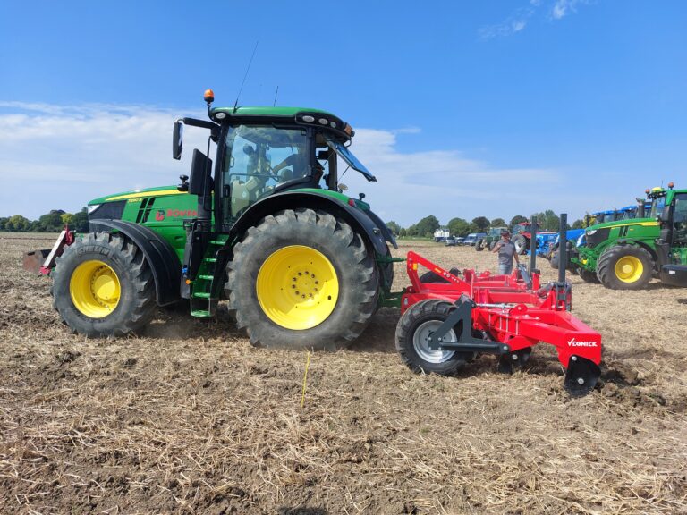 Groene trekker met rode woeler op perceel