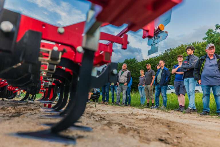 Mensen kijken naar machine in het veld tijdens velddemo