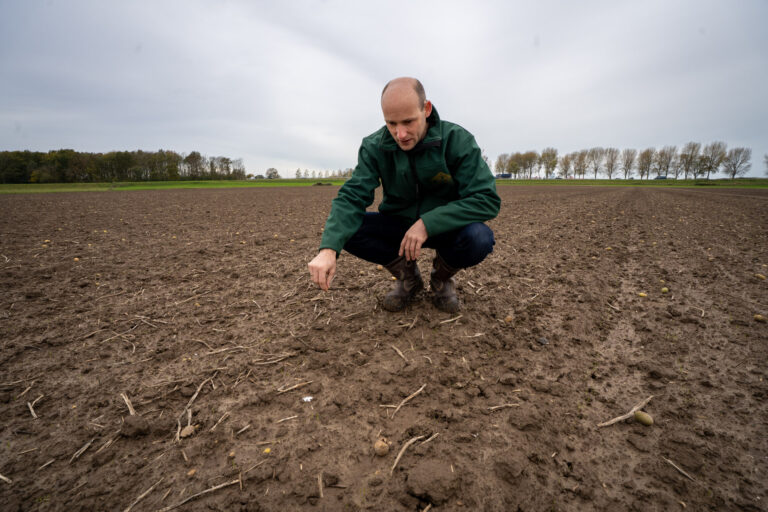 Akkerbouwer in het veld kijkend naar de bodem